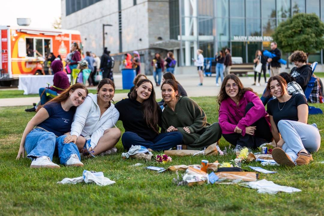 students sitting in the grass smiling